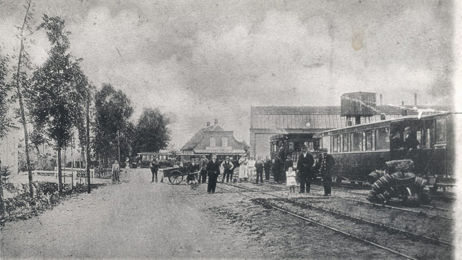 Prentbriefkaart van de tramremise in Drunen, met een tram en omstanders in de straat.